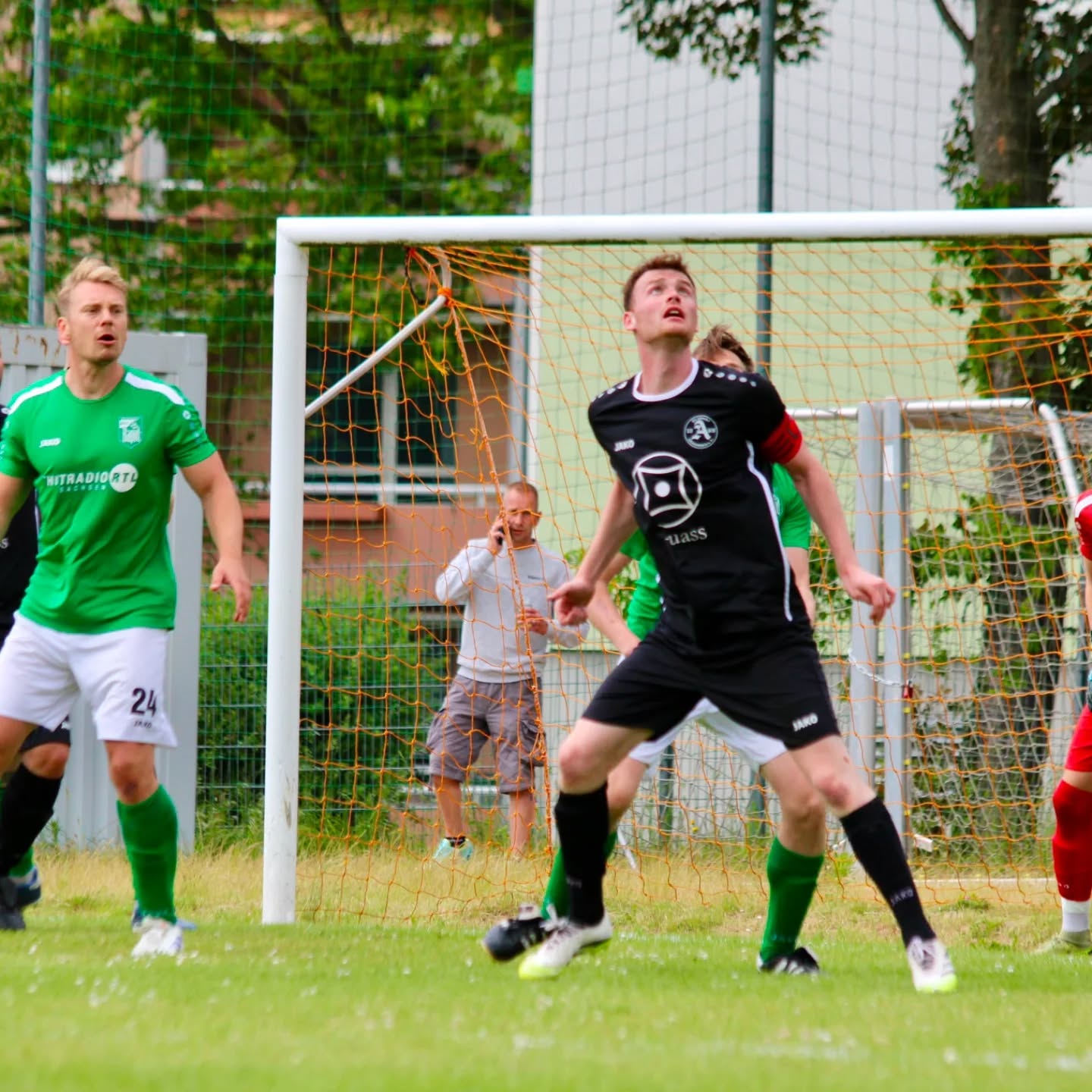 Zwei Spieler beobachten vor dem Tor den heranfliegenden Ball