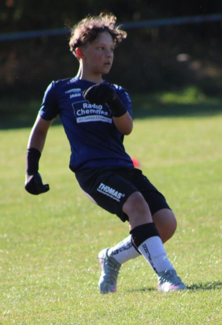Ein Nachwuchsspieler im dunkelblauen Trikot beobachtet das Spielgeschehen