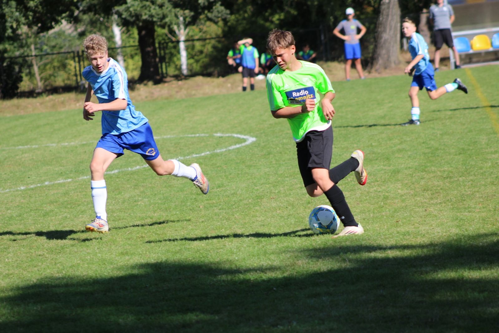 Zwei Nachwuchsspieler sprinten nebeneinander dem Ball hinterher