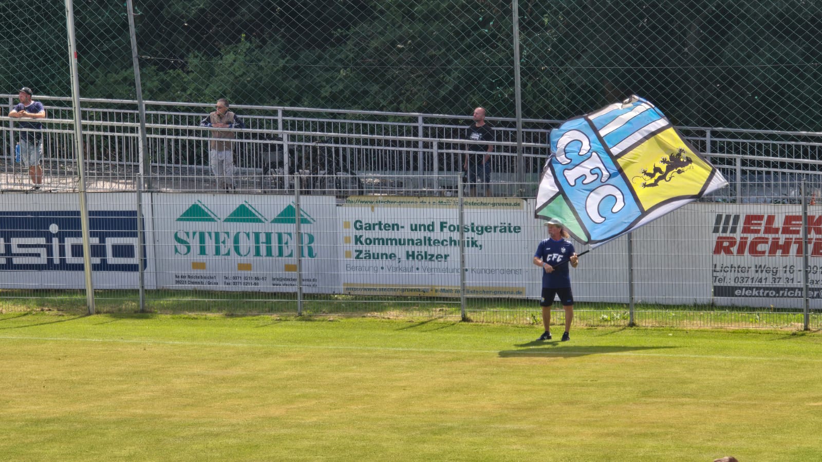 Ein Fan schwenkt am Spielfeldrand eine große Fahne