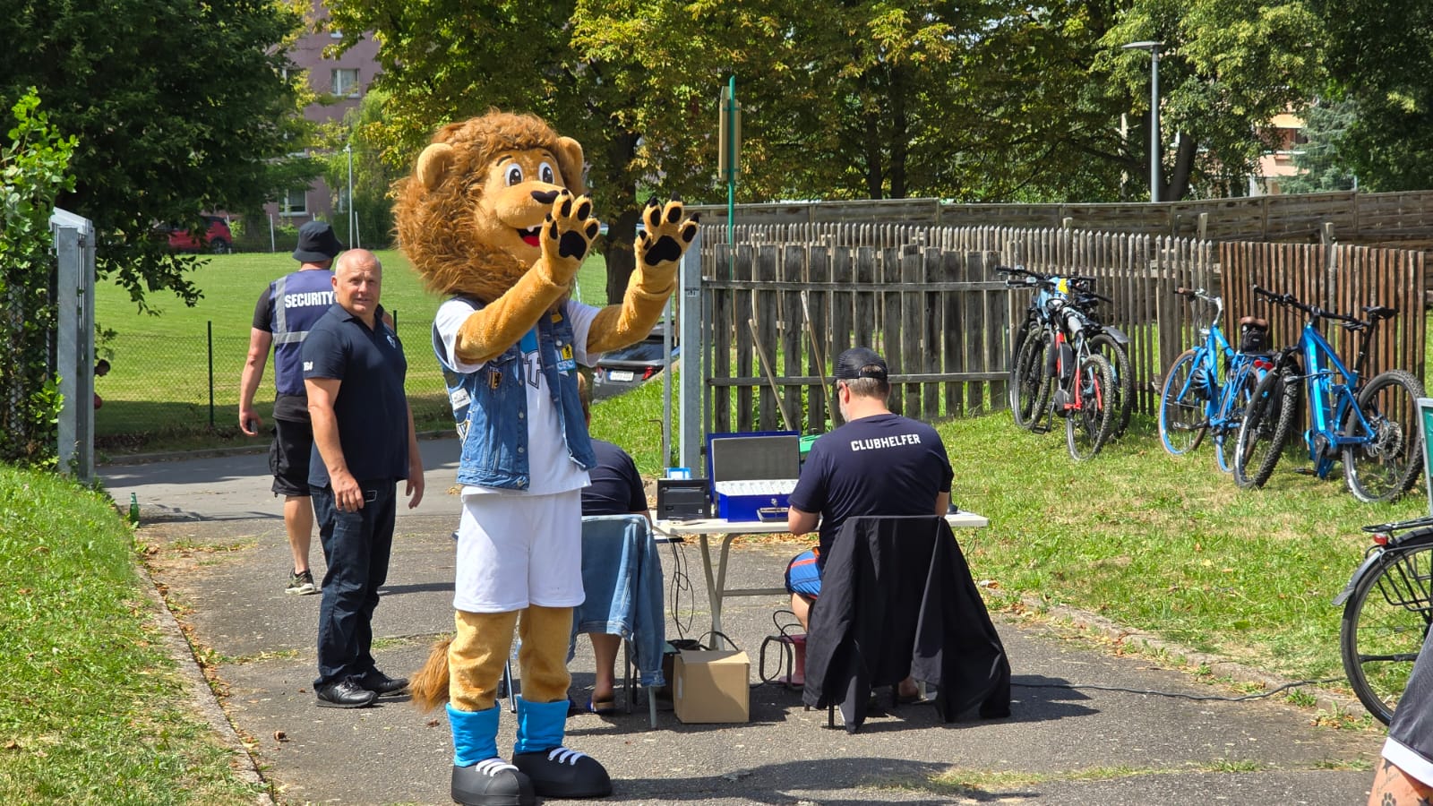 Ein Löwen-Maskottchen winkt neben dem Kassenstand am Eingang zur Sportanlage