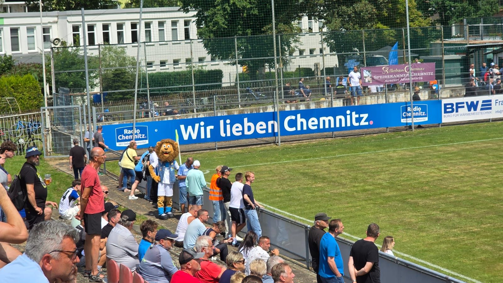 Zuschauerinnen und Zuschauer entlang der Bande mit der Aufschrift „Wir lieben Chemnitz“