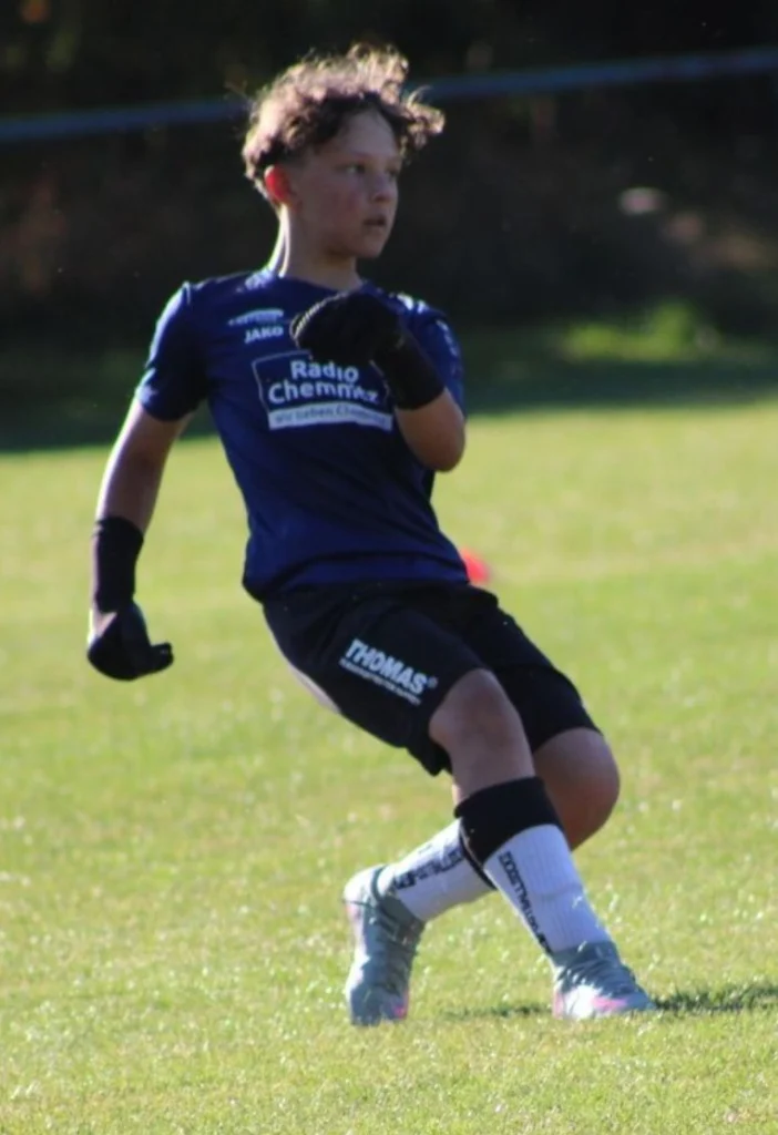 Ein Nachwuchsspieler im dunkelblauen Trikot beobachtet das Spielgeschehen