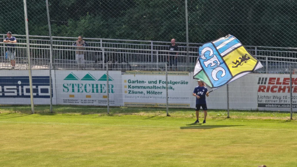 Ein Fan schwenkt am Spielfeldrand eine große Fahne